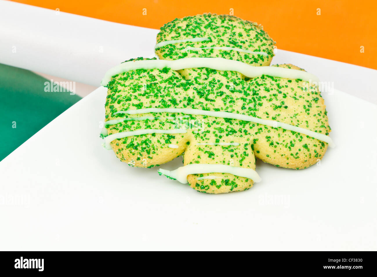 Cookie in Kleeblatt-Form auf weißen Teller auf die Farben der irischen Flagge gelegt. Stockfoto
