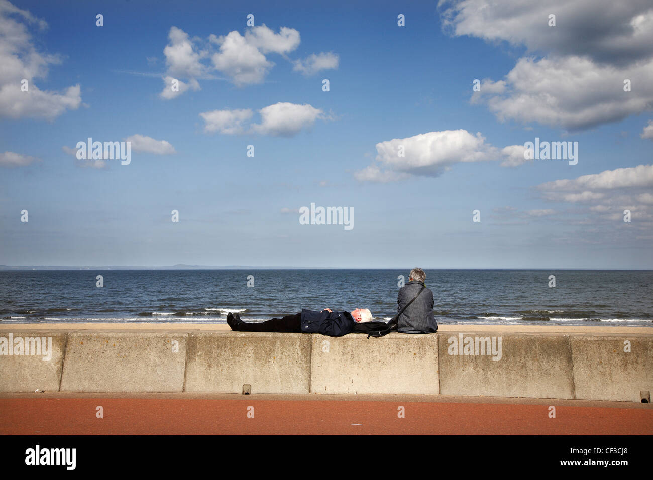 Ein älteres paar entspannende an der Strandpromenade von Portobello Beach entlang der Küste des Firth of Forth. Stockfoto