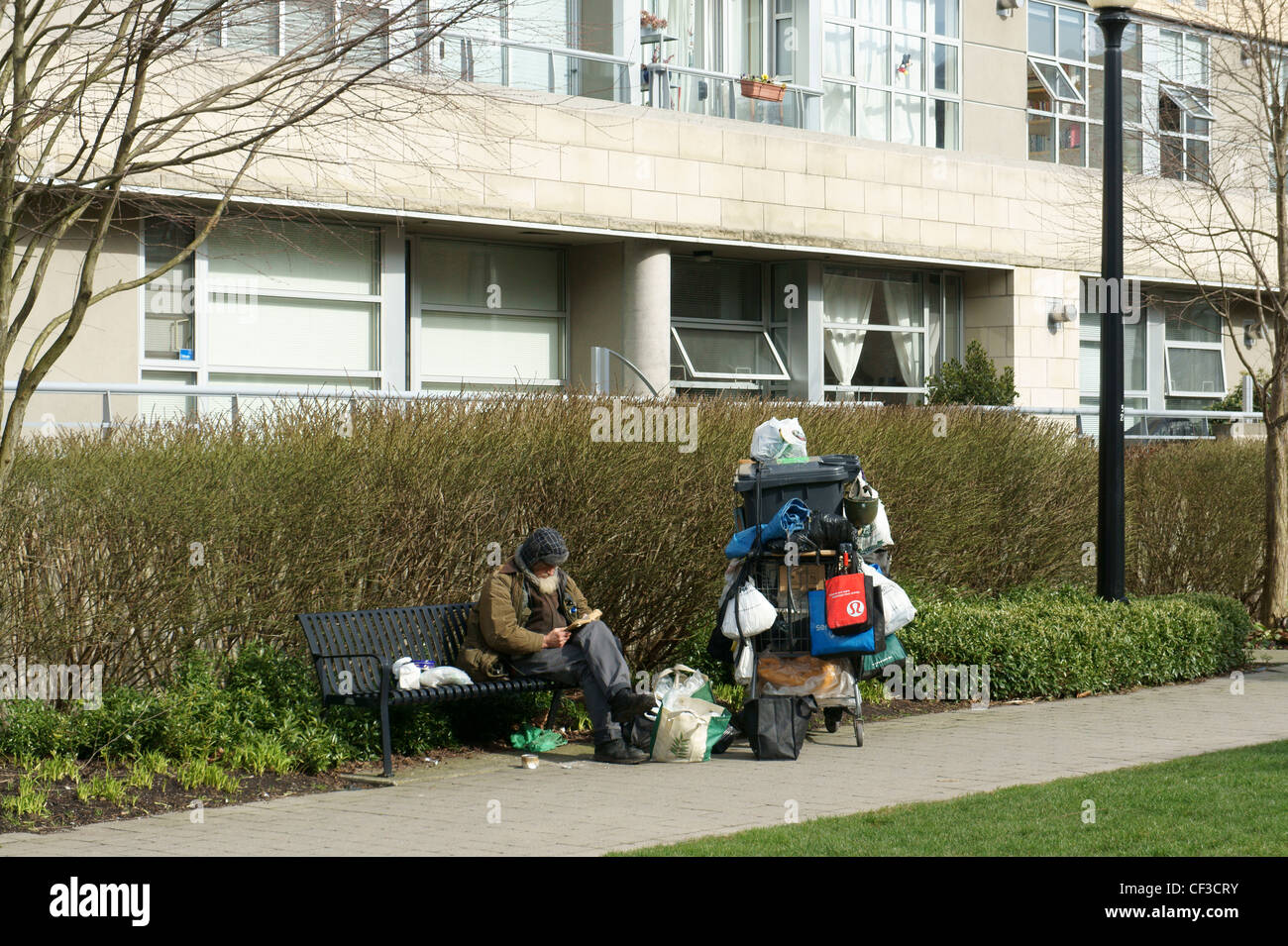 Obdachloser sitzen auf einer Bank, einem Buch, Vancouver, Britisch-Kolumbien, Kanada Stockfoto
