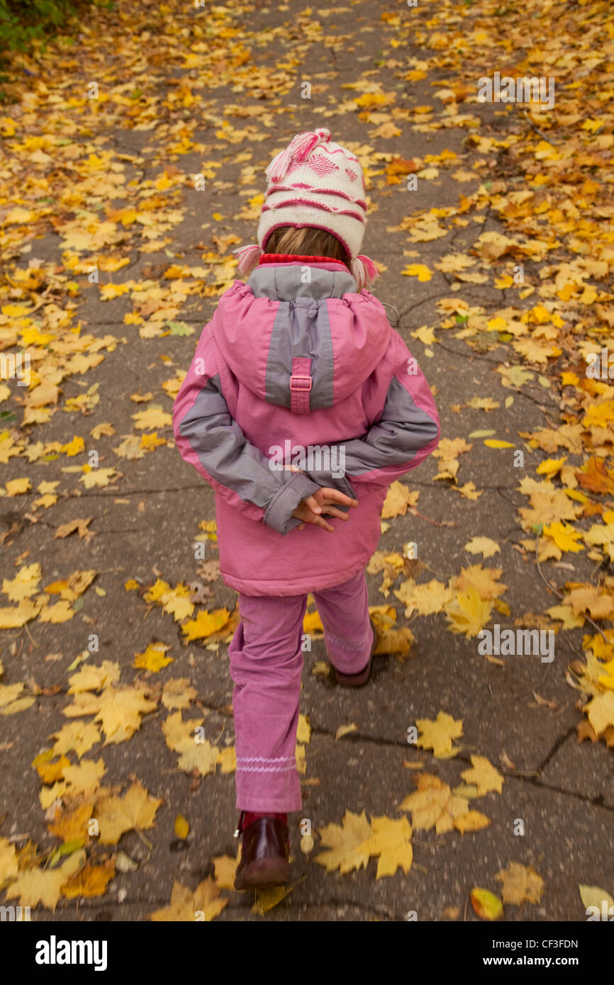 Kleines Mädchen in Rosa Kleidung gehen zu Fuß auf herbstlichen Park allein Stockfoto