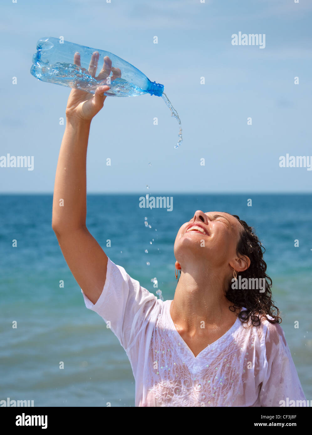 Mädchen-Spritzwasser über sich selbst aus der Flasche, heißen sonnigen Tag am Strand. Stockfoto