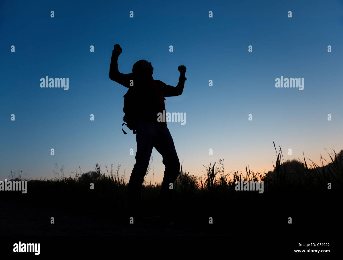 Silhouette des Mannes mit rised Hände am dunklen Himmel Stockfoto