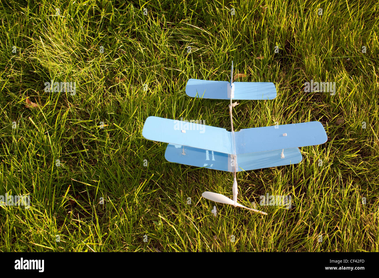 blaue Flugzeug Spielzeugflugzeug auf grüner Wiese Boden. Ansicht von oben Stockfoto