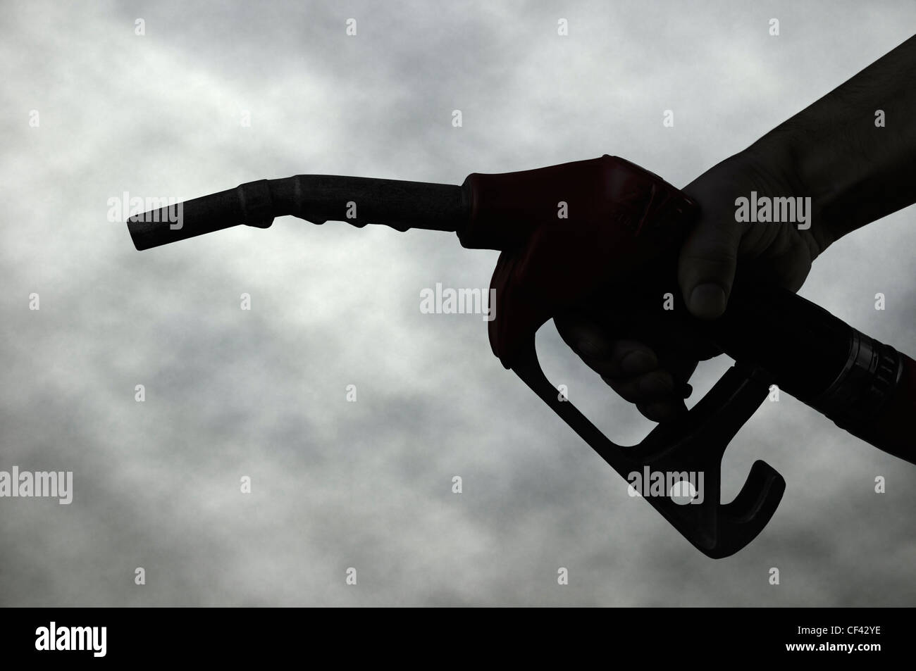 Hand mit einem Benzin-Pumpe-Düse Silhouette gegen ein dunkel bewölkter Himmel. Stockfoto