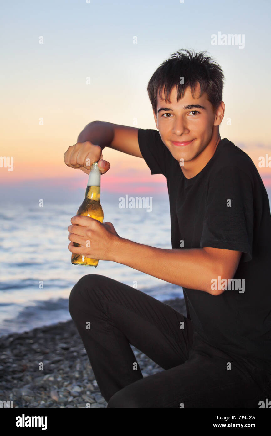 Teenager Boy öffnet Abend Bier Abfüller am Ufer des steinernen Meeres Stockfoto