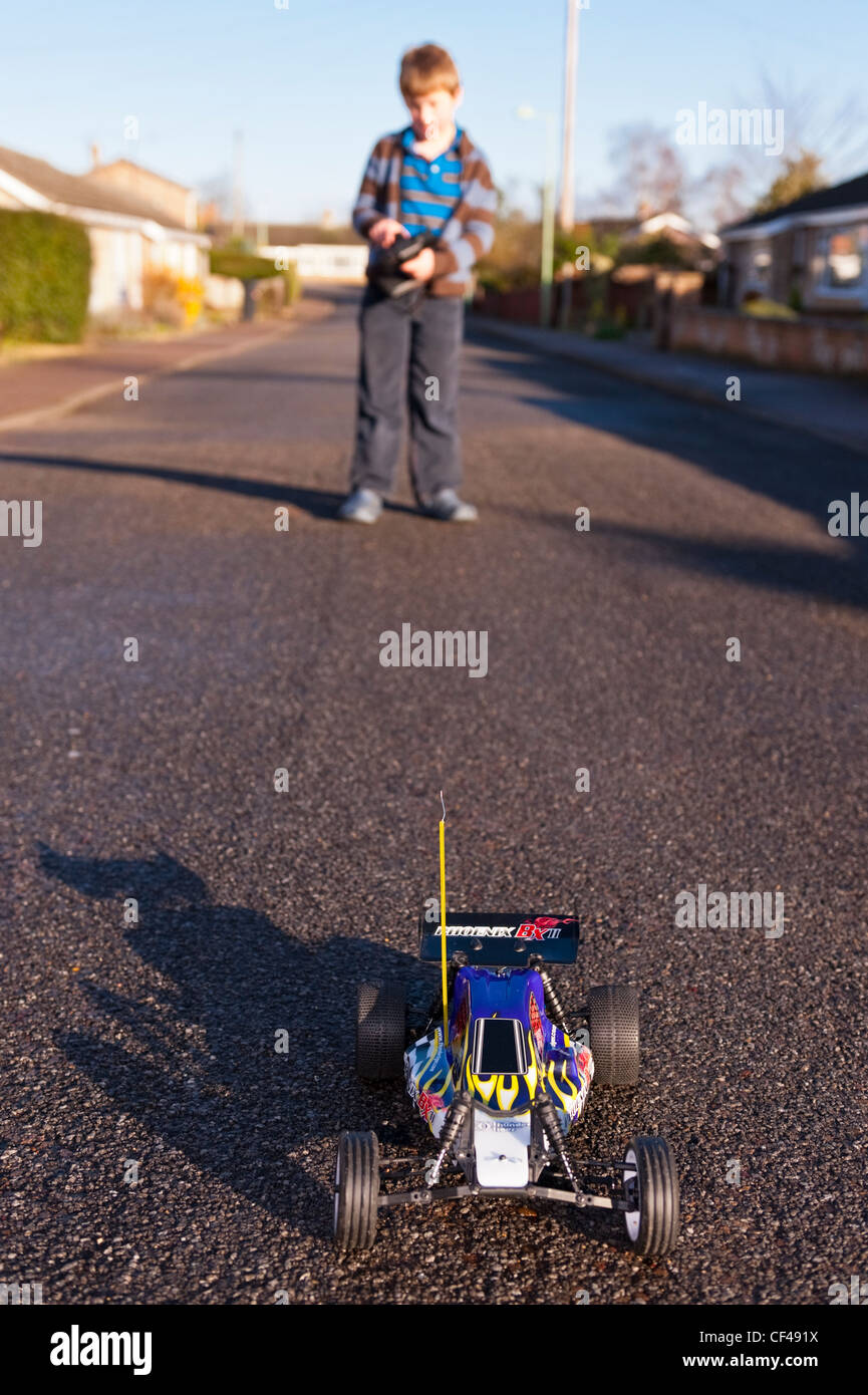 Ein 8 Jahre alter Junge spielt mit seinem Radio gesteuerten Auto auf der Straße in England, Großbritannien, Uk Stockfoto