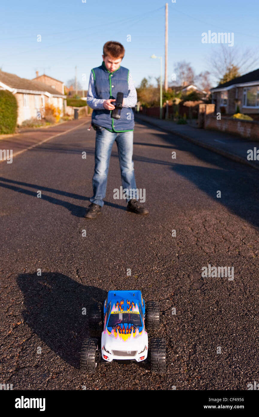 Ein 12-jähriger Junge spielt mit seinem Radio gesteuerten Auto auf der Straße in England, Großbritannien, Uk Stockfoto