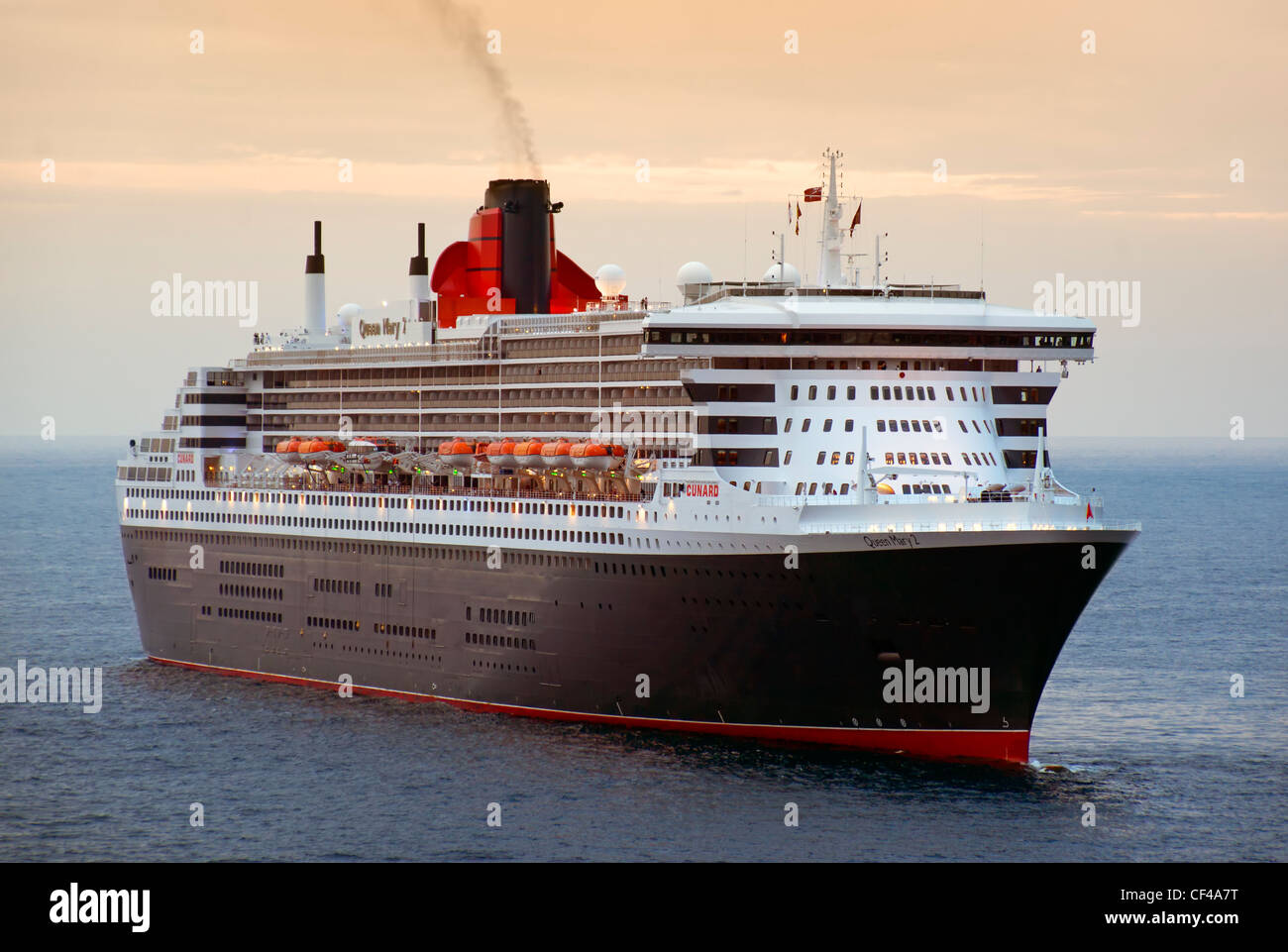 RMS Queen Mary 2, der größte Ozeandampfer, die jemals gebaut wurde, aus dem Hafen von Monaco in der Abenddämmerung. Stockfoto