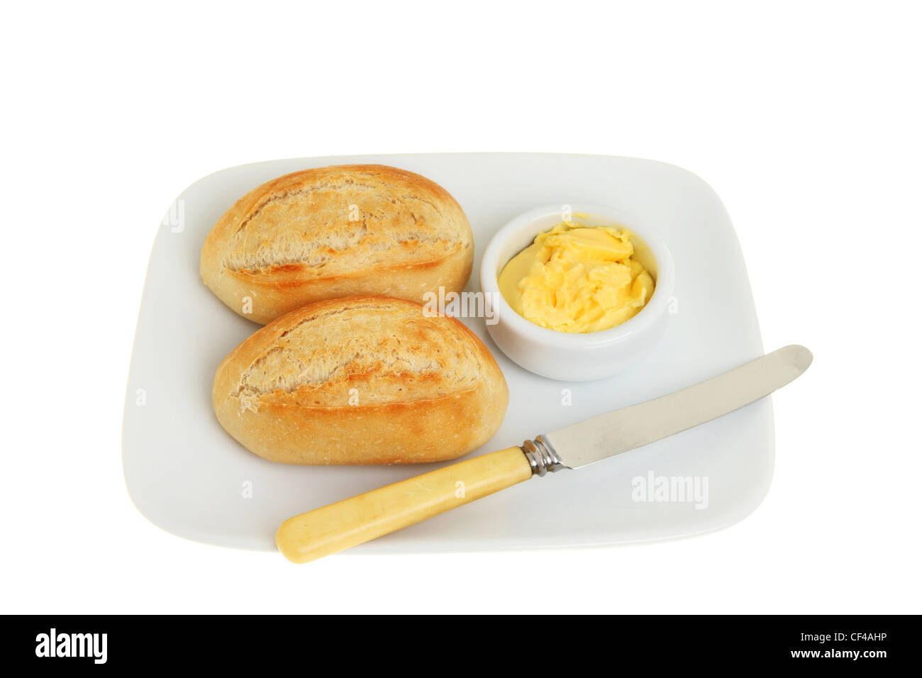 Zwei Brötchen petit Pain mit Butter und ein Messer auf einem Teller isoliert gegen weiß Stockfoto