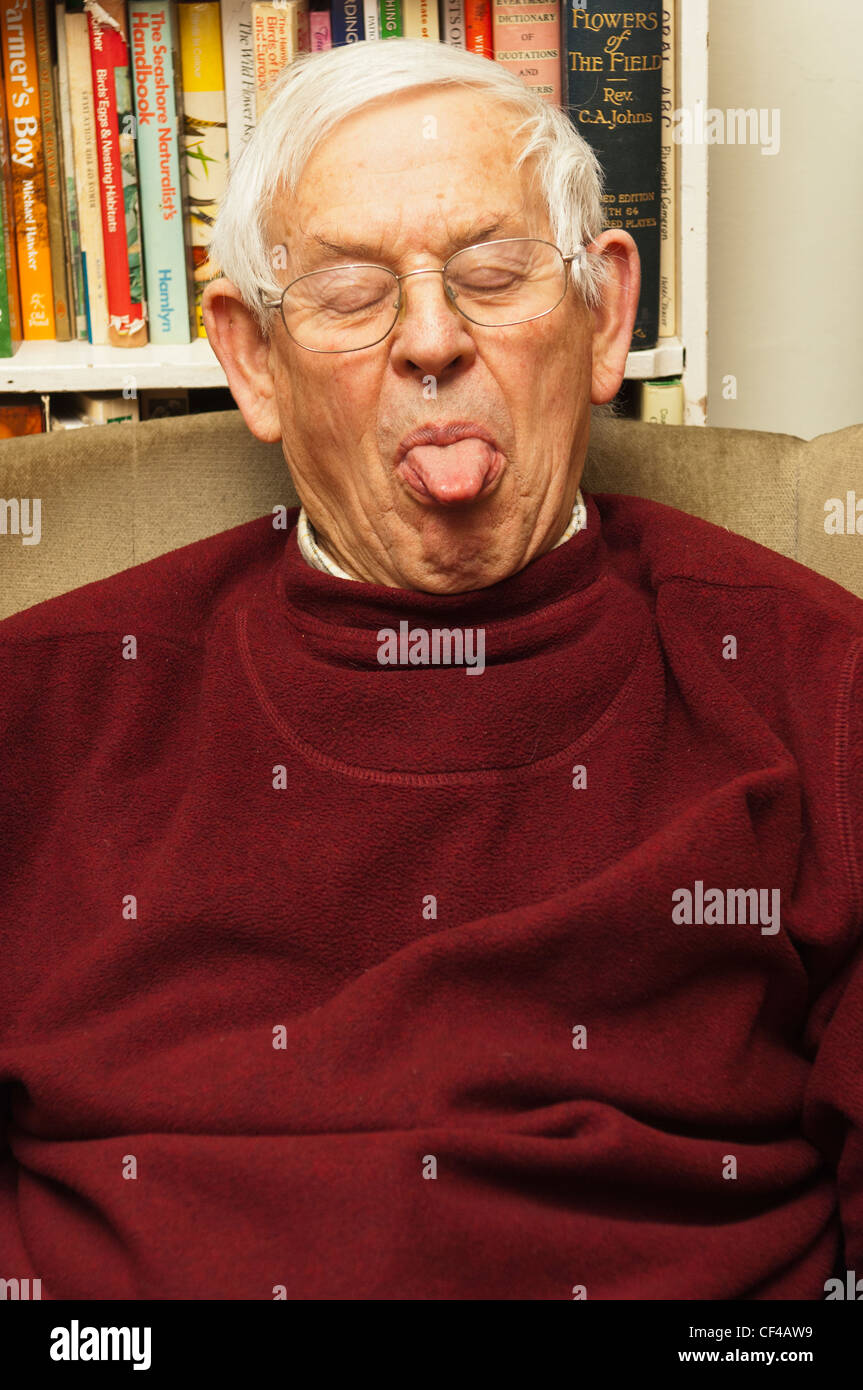 Ein senior ältere Mann in seinem 80 ist ein lustiges Gesicht zu Hause in England, Großbritannien, Vereinigtes Königreich ziehen. Stockfoto