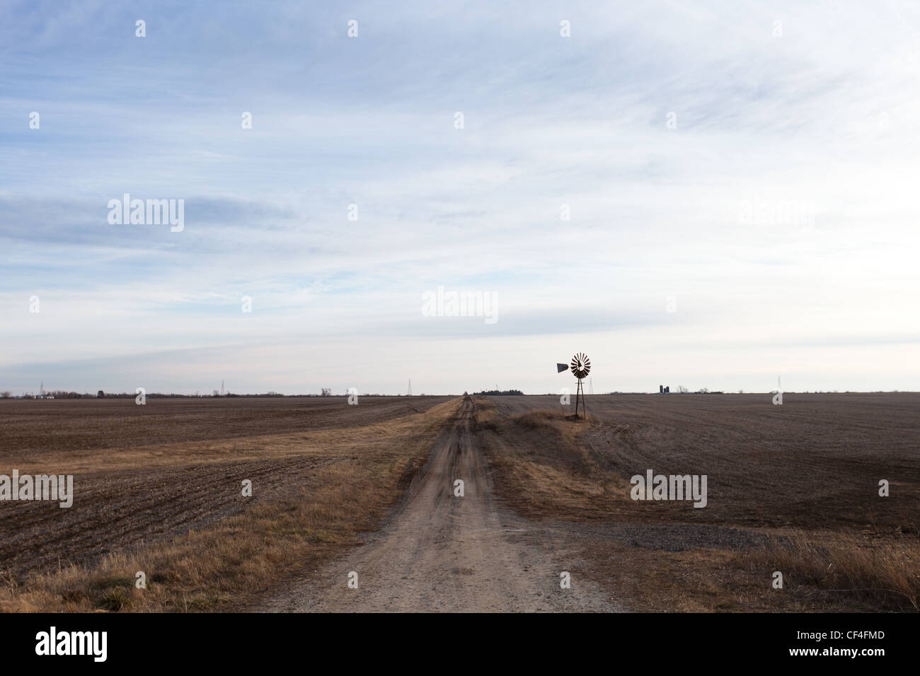 Einem einsamen Feldweg im ländlichen Illinois mit einer Windmühle, die über den braunen Feldern sprießen. Stockfoto