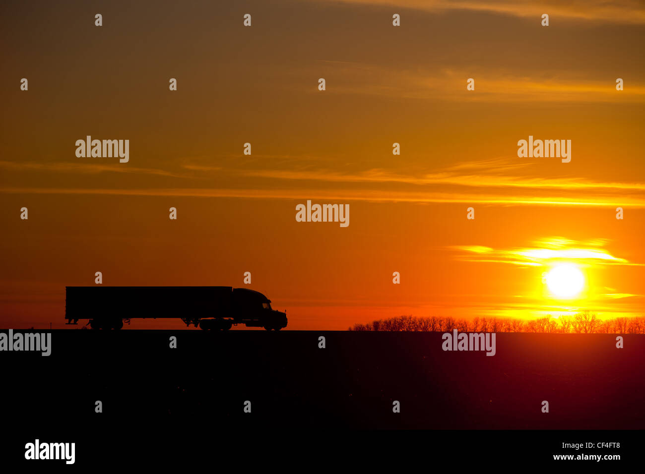 Eine halb Traktor Anhänger Rig bewegt sich die Autobahn in Zentral-Illinois gegen einen farbenprächtigen Sonnenuntergang. Stockfoto
