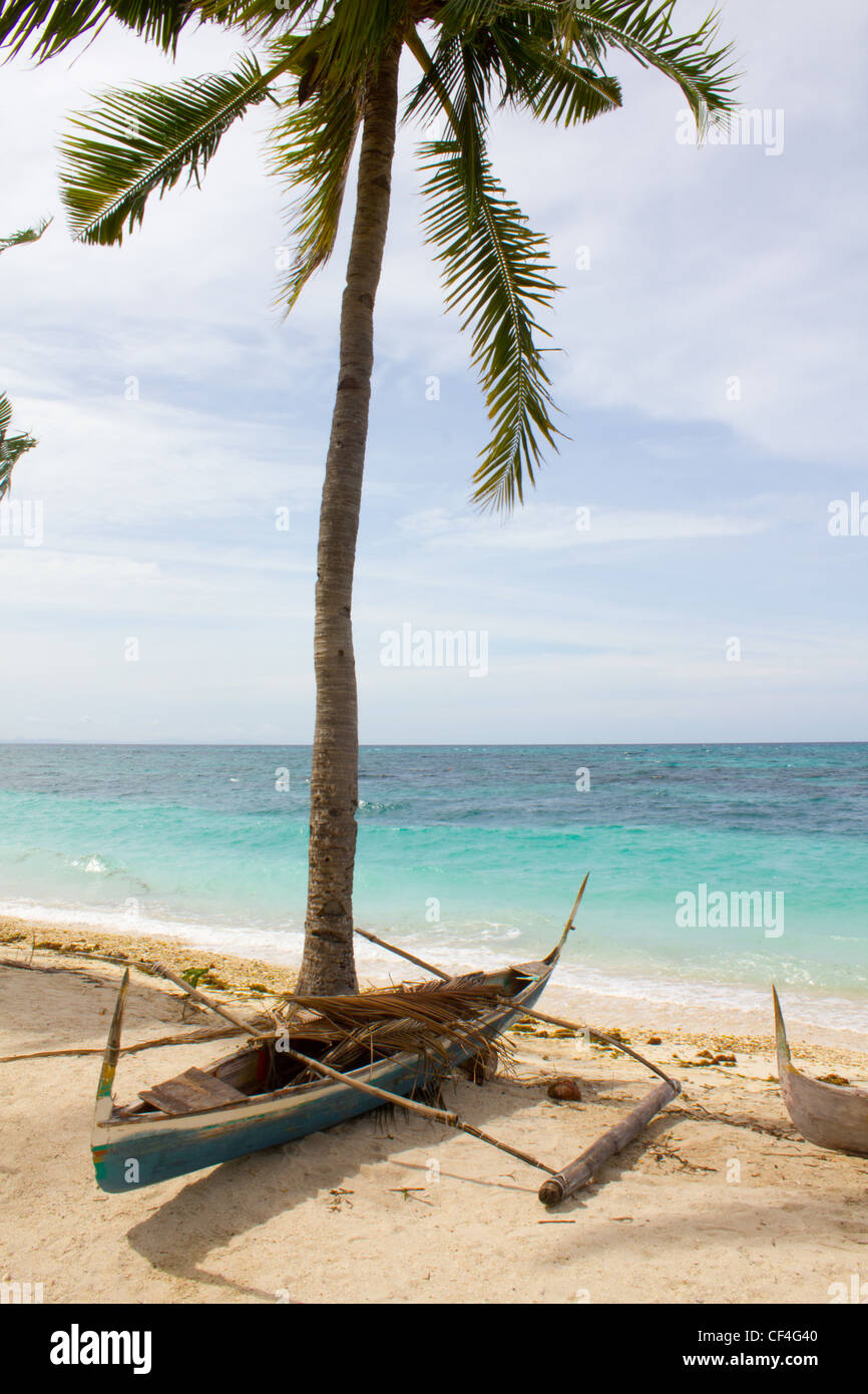Ein kleines Boot liegt unter schattigen Palmen an einem abgelegenen Insel Strand Stockfoto