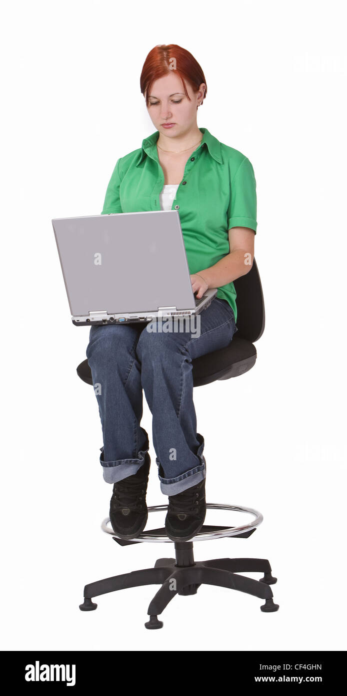 Rothaarige Teenager auf einem hohen Stuhl sitzen und arbeiten auf einem Laptop. Stockfoto