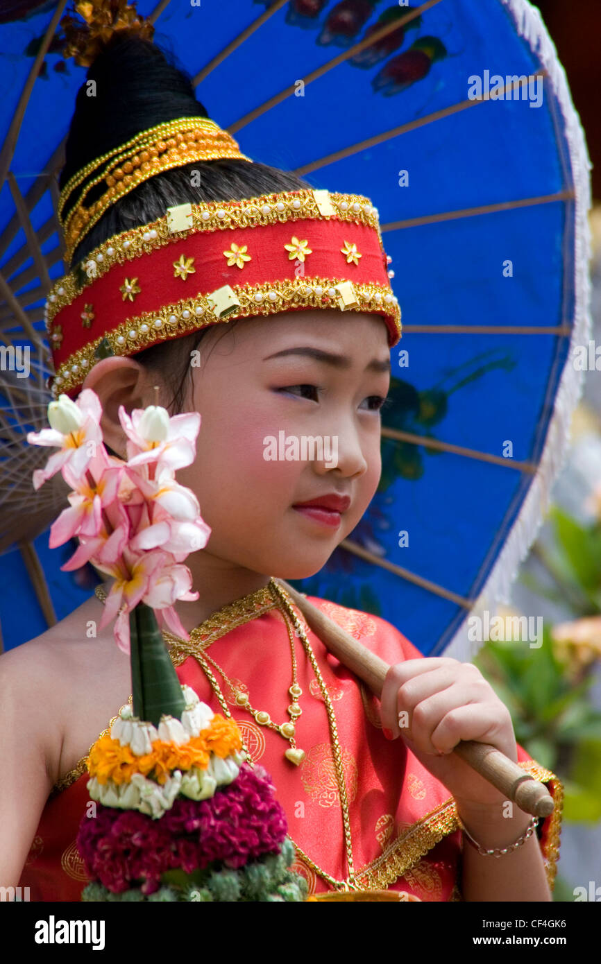 Eine junge Asiatin s hält einen Regenschirm und Blumen auf dem Lao Neujahr Festival in Luang Prabang, Laos. Stockfoto