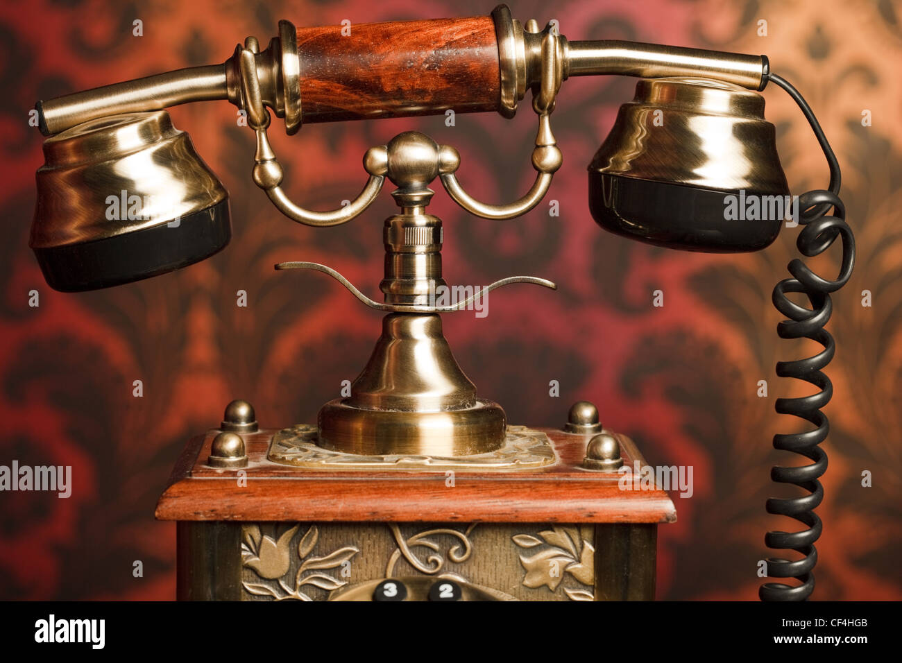 Fragment von einem alten Handy gemacht aus Metall mit Holzgriff. gegen die Arnament zurückgezogen Stockfoto