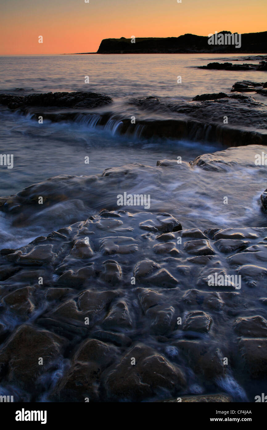 Die Flut rollt felsigen Kalkstein leisten in der Hobarrow Bucht auf Dorset Jurassic Coast bei Sonnenuntergang. Stockfoto