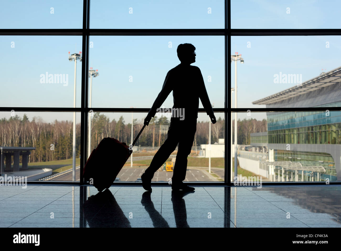 Silhouette des Mannes mit Gepäck zu Fuß direkt in der Nähe von Fenster in Flughafen Stockfoto