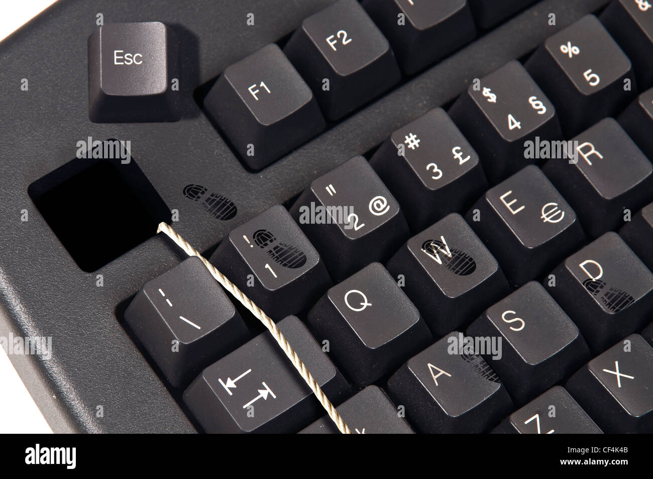 Computer-Tastatur mit einem Seil und Fußabdrücke aus der Esc-Taste. Stockfoto