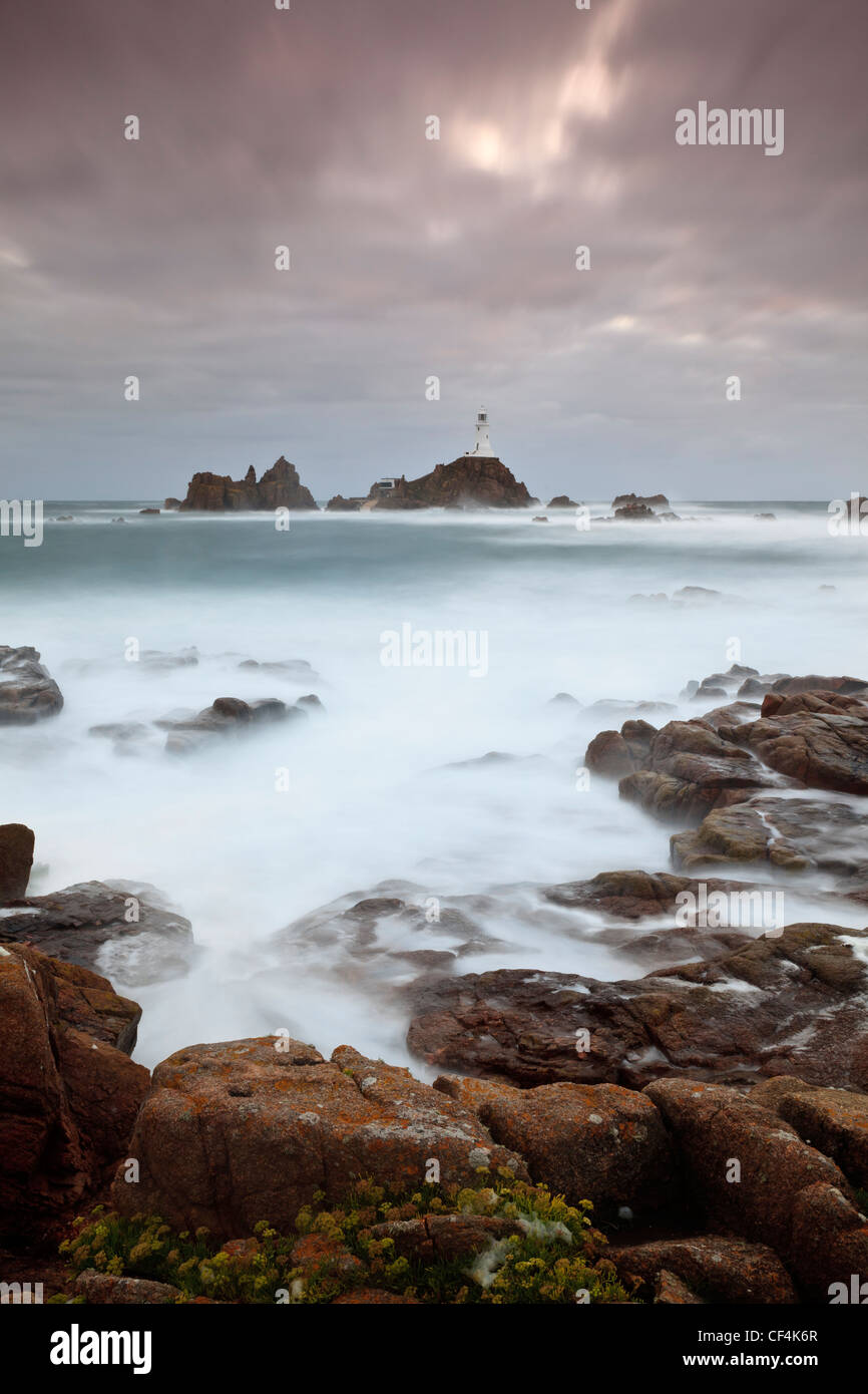 Raue See rund um La Corbiere Leuchtturm bei Sonnenuntergang. Der Leuchtturm war der erste auf den britischen Inseln aus Beton gebaut werden. Stockfoto