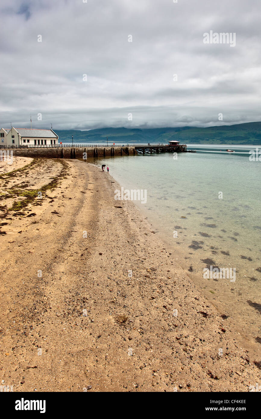 Der Strand neben dem Teil Stein, Teil eisernen Pier in der kleinen Ortschaft Beaumaris über die Menaistraße in Anglesey. Stockfoto
