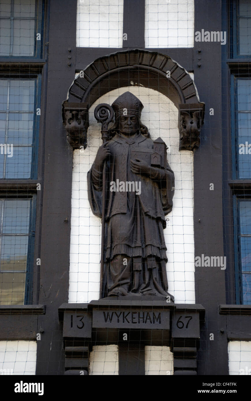 Statue William von Wykeham, Bischof von Winchester auf der Außenseite eines Tudor Gebäudes in Winchester High Street. Stockfoto