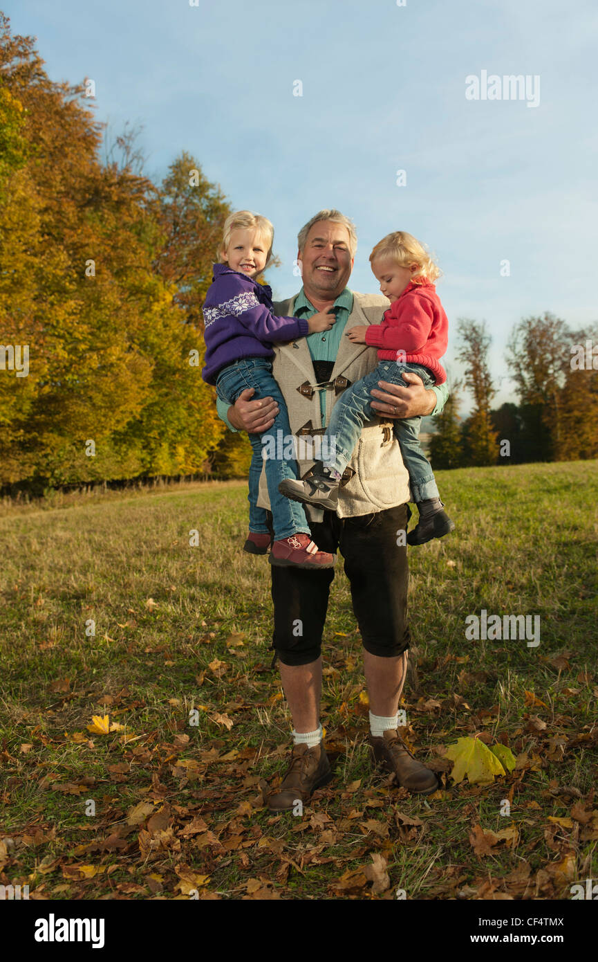 Deutschland, Bayern, Großvater mit Enkelinnen im Herbst, Lächeln Stockfoto
