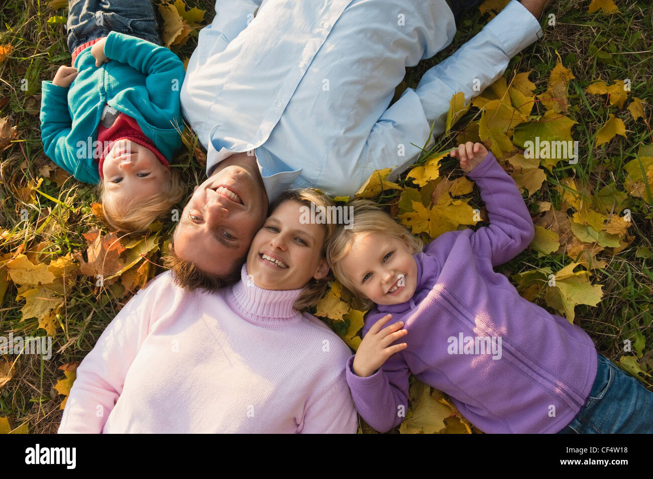 Deutschland, Bayern, Familie liegen auf Blätter im Herbst, Porträt, Lächeln Stockfoto