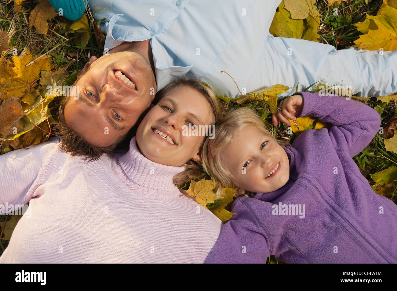 Deutschland, Bayern, Familie liegen auf Blätter im Herbst, Lächeln Stockfoto