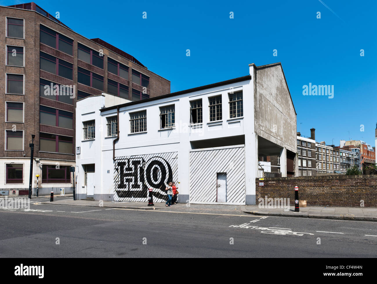 Zwei Frauen zu Fuß vorbei an einem Gebäude auf Lindsey Street, Fensterläden von Ben Eine, ein Straßenkünstler Notab Smithfield mit "HQ" aufgemalt. Stockfoto