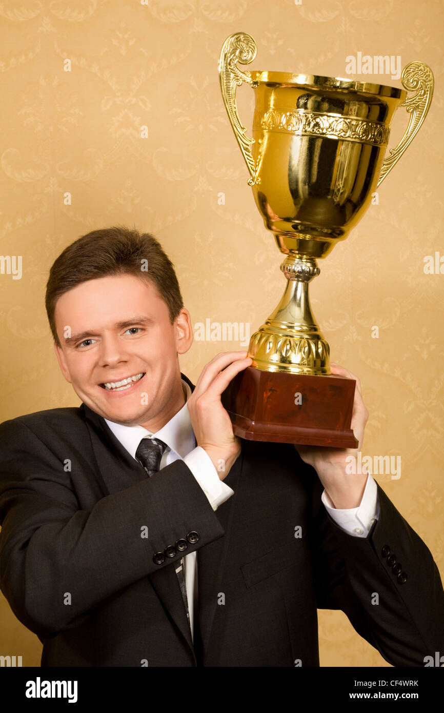 lächelnd Geschäftsmann im Anzug mit Win-Cup in der hand Stockfoto