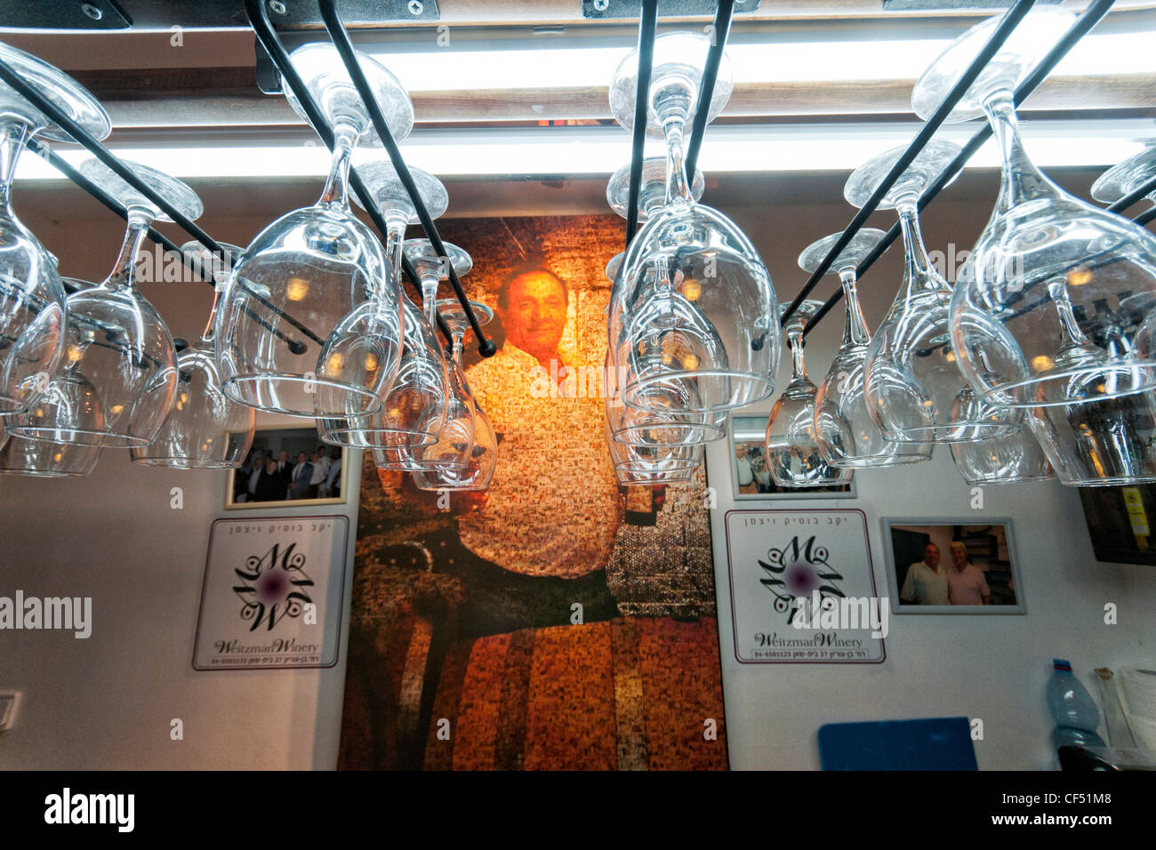 Wette Shean, Israel. Der Speicher des Weinguts Weizmann Boutique. Brille von Schienen hängen; Des Eigentümers Porträt im Hintergrund. Stockfoto