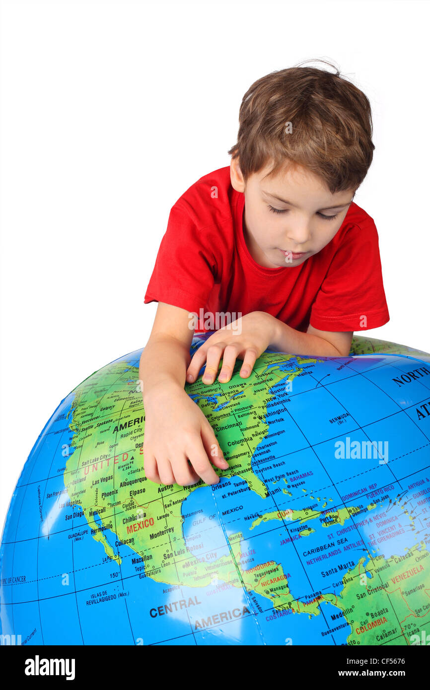 Junge im roten Hemd lehnt sich auf aufblasbaren Globus isoliert auf weißem Hintergrund Stockfoto