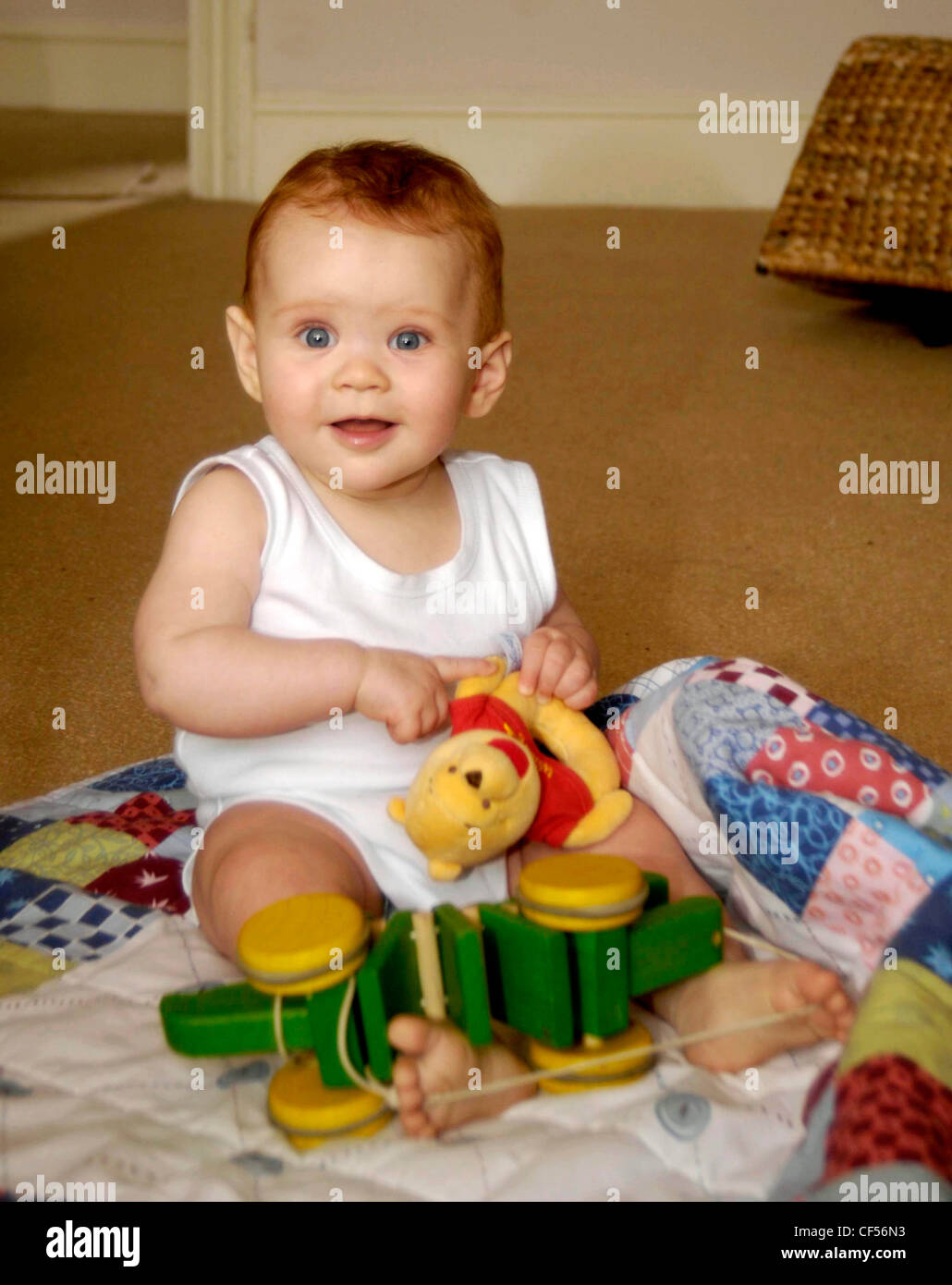 Weibliches Kind sitzt auf Patchwork quilt spielen nachschlagen zu Kamera Lächeln Stockfoto