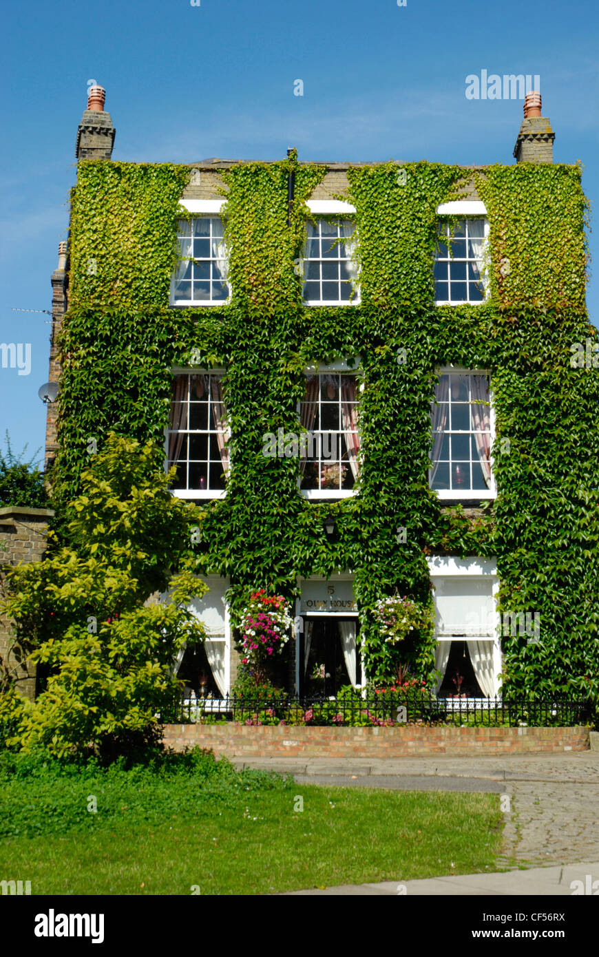 Ein blauer Himmel Hintergrund für den Efeu bedeckt Quay House Hotel in Ely. Stockfoto