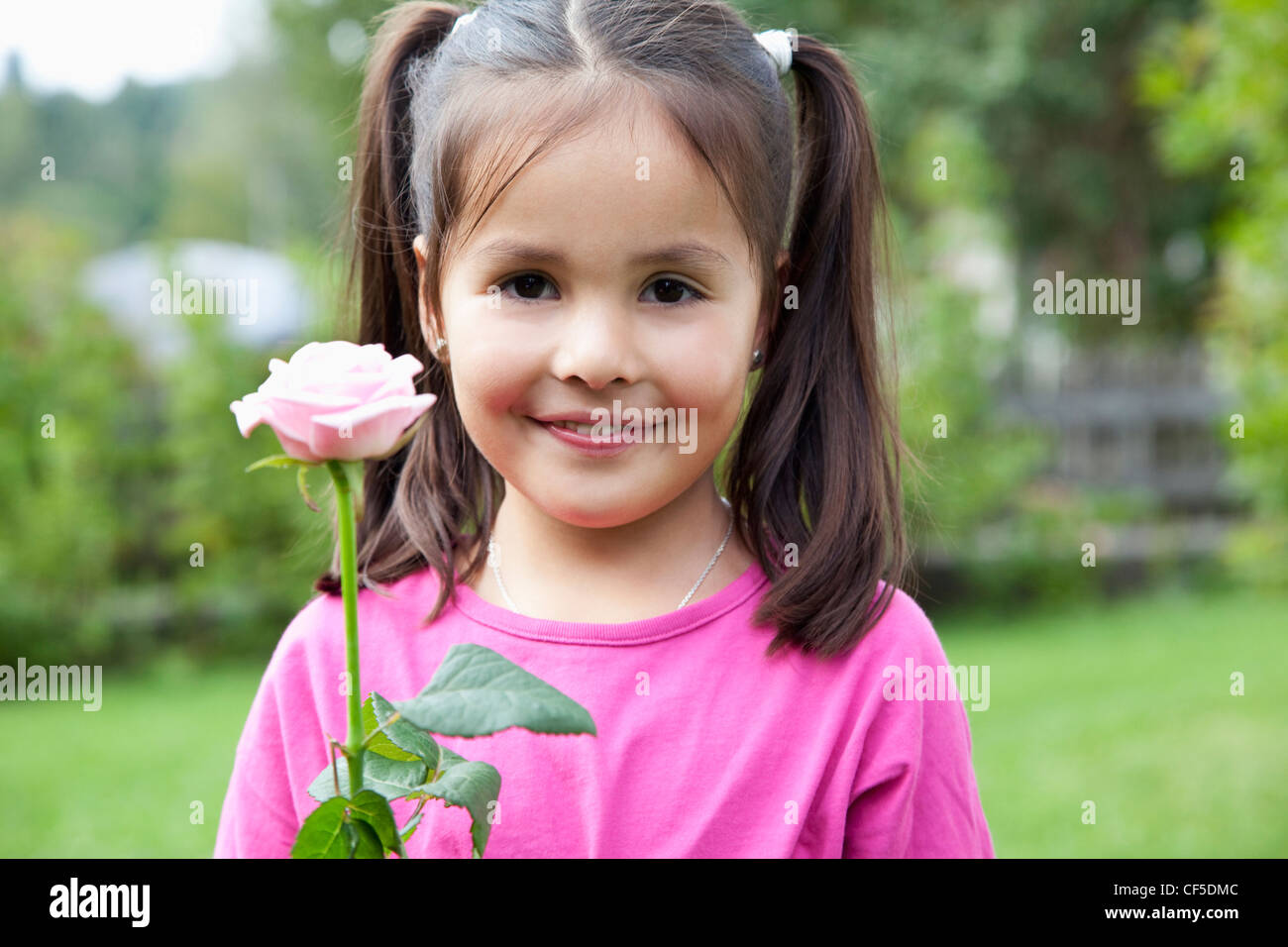 Deutschland, Bayern, Huglfing, Mädchen mit Blume im Garten, Lächeln, Porträt Stockfoto