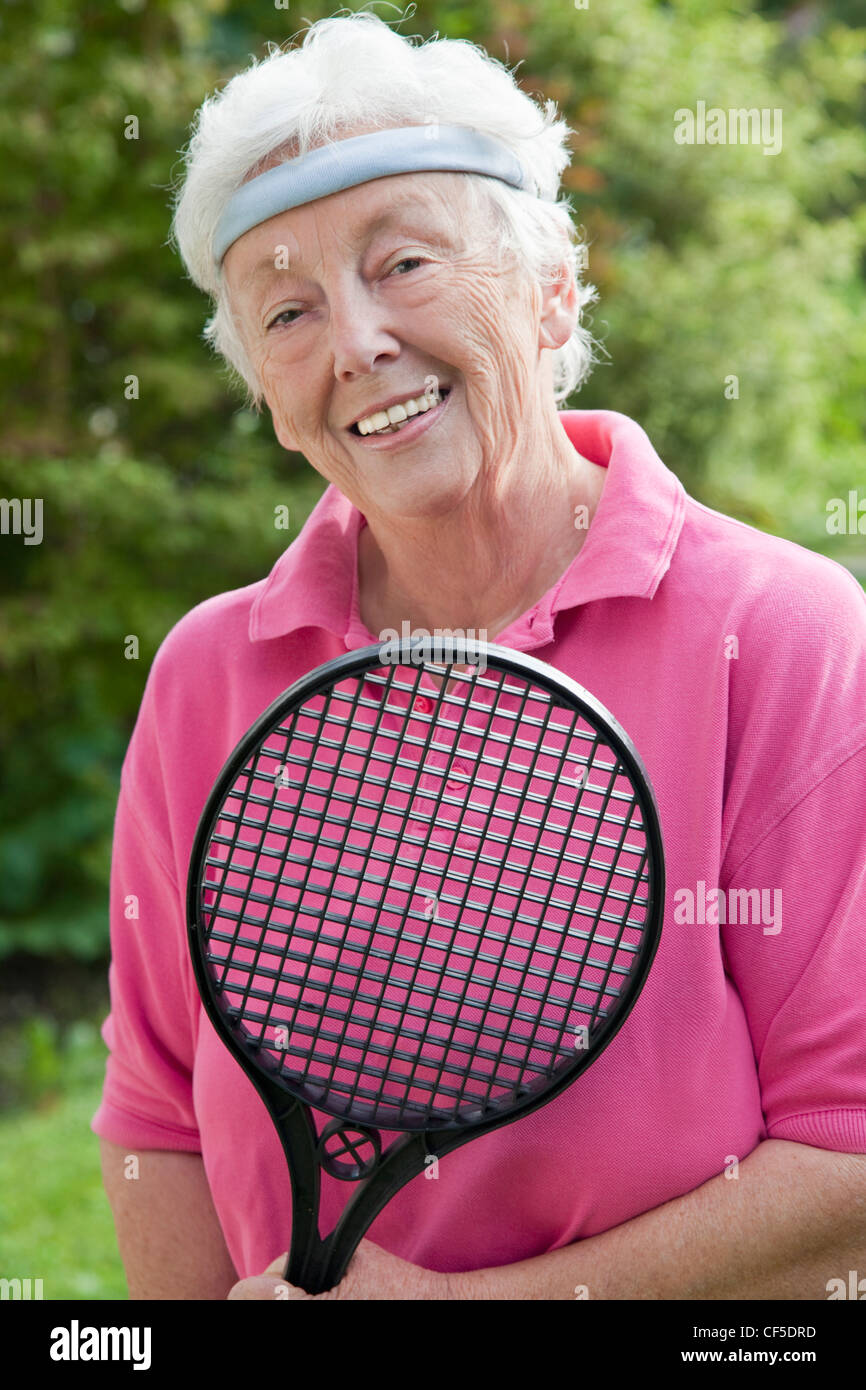 Deutschland, Bayern, Huglfing, Senior Frau hält Federballschläger, Lächeln, Porträt Stockfoto