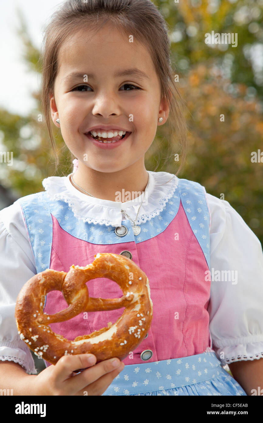 Deutschland, Bayern, Huglfing, Mädchen Holding Brezel im Garten, Lächeln, Porträt Stockfoto