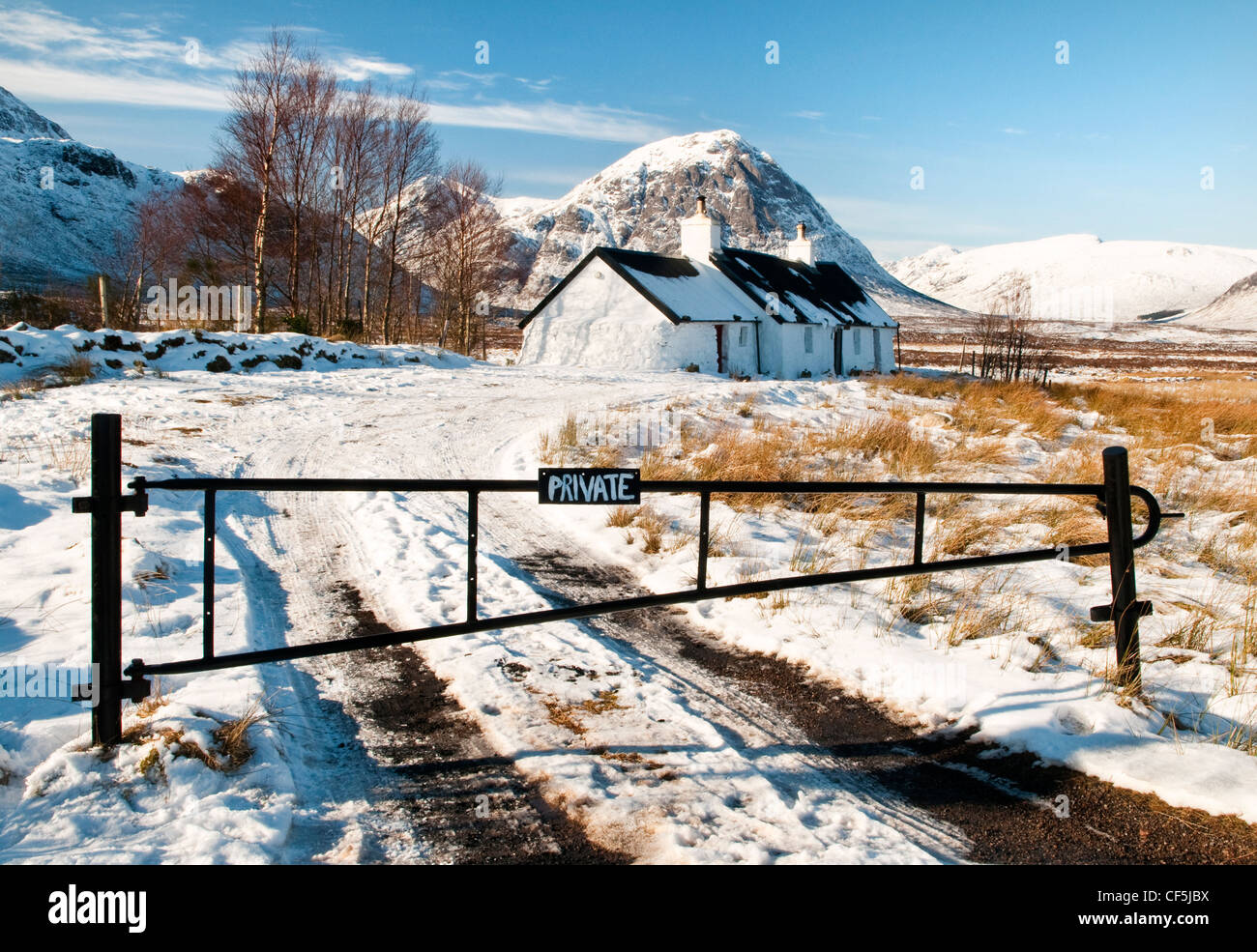 Ein Tor über eine verschneite Fahrt führt zu Black Rock Cottage in Glencoe. Stockfoto