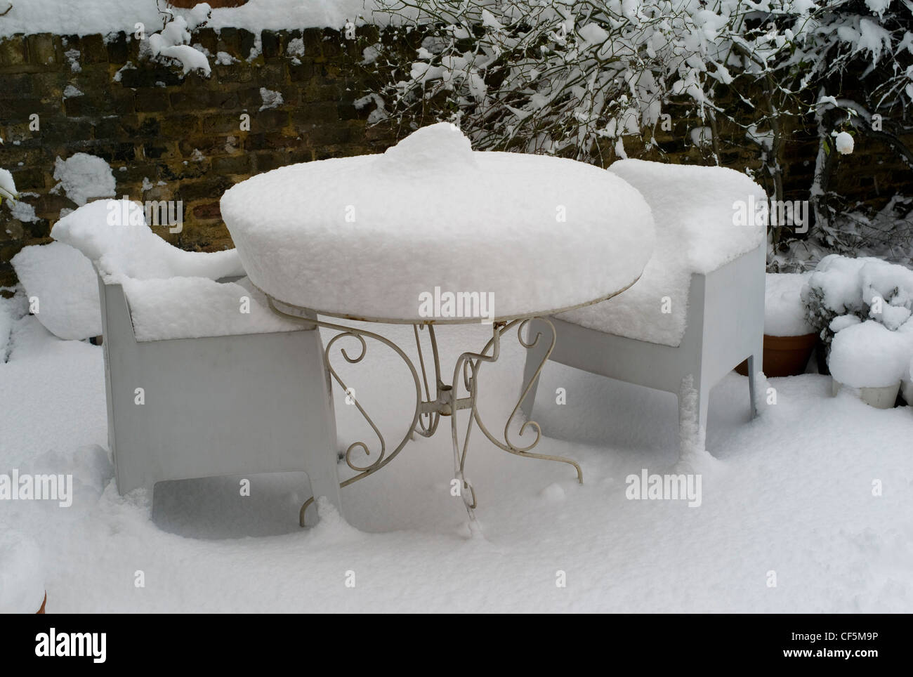 Ein Blick auf einen Garten bedeckt im Schnee mit einem Tisch und zwei Stühle mit einer dicken Schicht Schnee über Sie Stockfoto