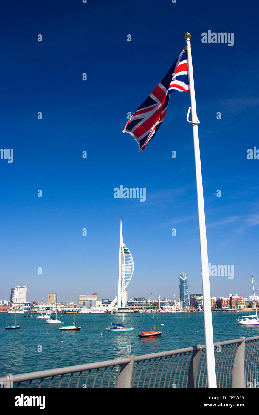 Ein Union Jack-Flagge an der Uferpromenade in Gosport gegenüber der 170m hohe Spinnaker Tower in Gunwharf Quays in Portsmouth Har Stockfoto