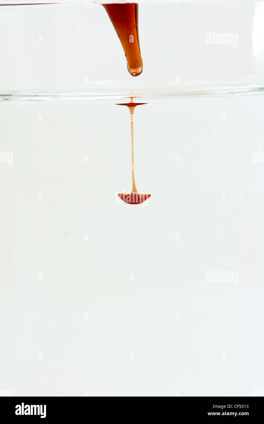 Ein Tropfen rote Flüssigkeit in klare Flüssigkeit aus einer pipette Stockfoto