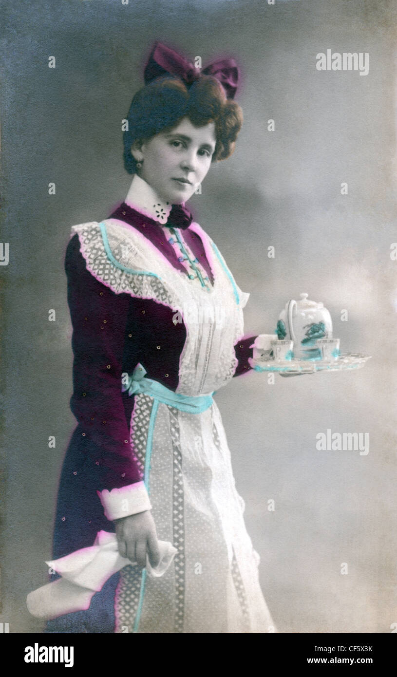 Ein Dienstmädchen gekleidet in ihrer Uniform und Schürze serviert Tee, um 1910. Stockfoto