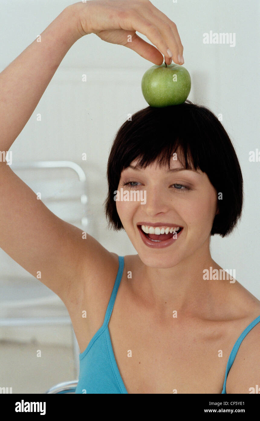 Eine Frau auf der Suche auf der linken Seite mit einem grünen Apfel auf den Kopf Stockfoto