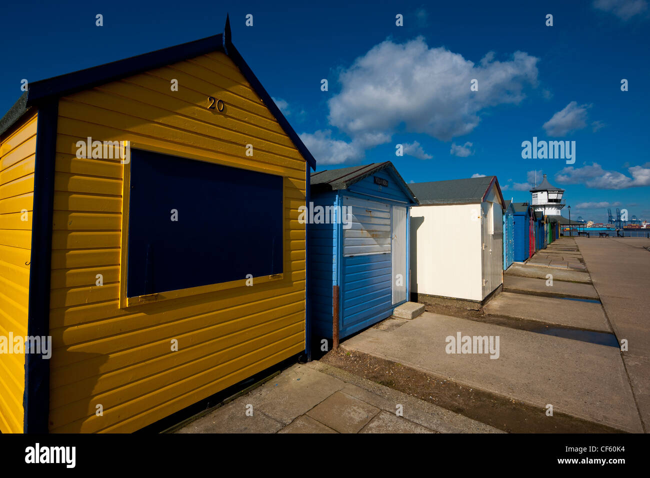 Frisch gestrichene Strandhütten am Strand von Harwich. Felixstowe Docks können im Hintergrund zu sehen. Stockfoto