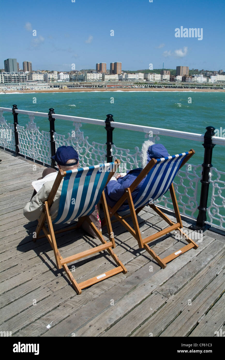 Zwei ältere Menschen sitzen in Liegestühlen am Pier von Brighton. Stockfoto