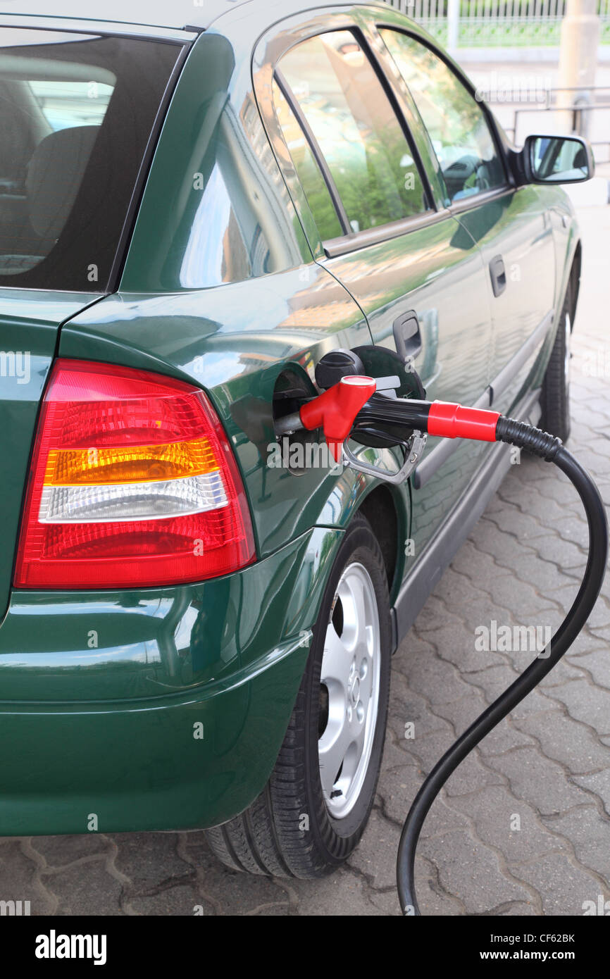 rote Pumpe für das Betanken füllen grünes Auto auf Station, Sommerzeit, Ansicht von hinten Stockfoto