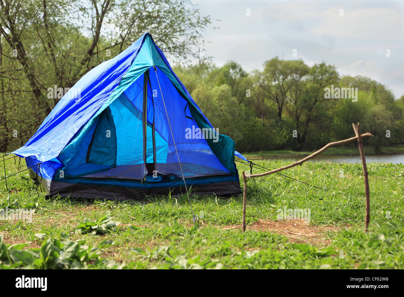 Blaue bereitgestellten Zelt steht am Ufer des Flusses im grünen Wald auf Sommertag Stockfoto