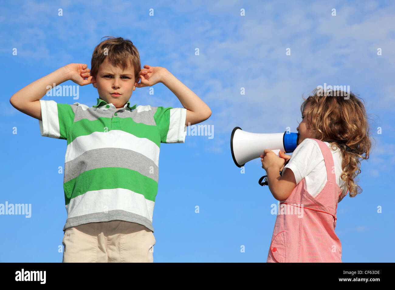 Kinder spielen auf Natur, Mädchen schreit im Lautsprecher, junge Ohren geschlossen hat. Stockfoto