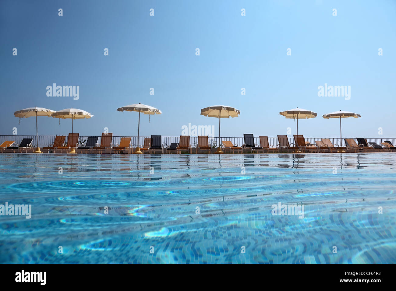 Am Rand des Pools in der Nähe von Zaun Liegestühle stehen Sie mit geöffneten Sonnenschirmen, Unterwasser Paket erschossen Stockfoto